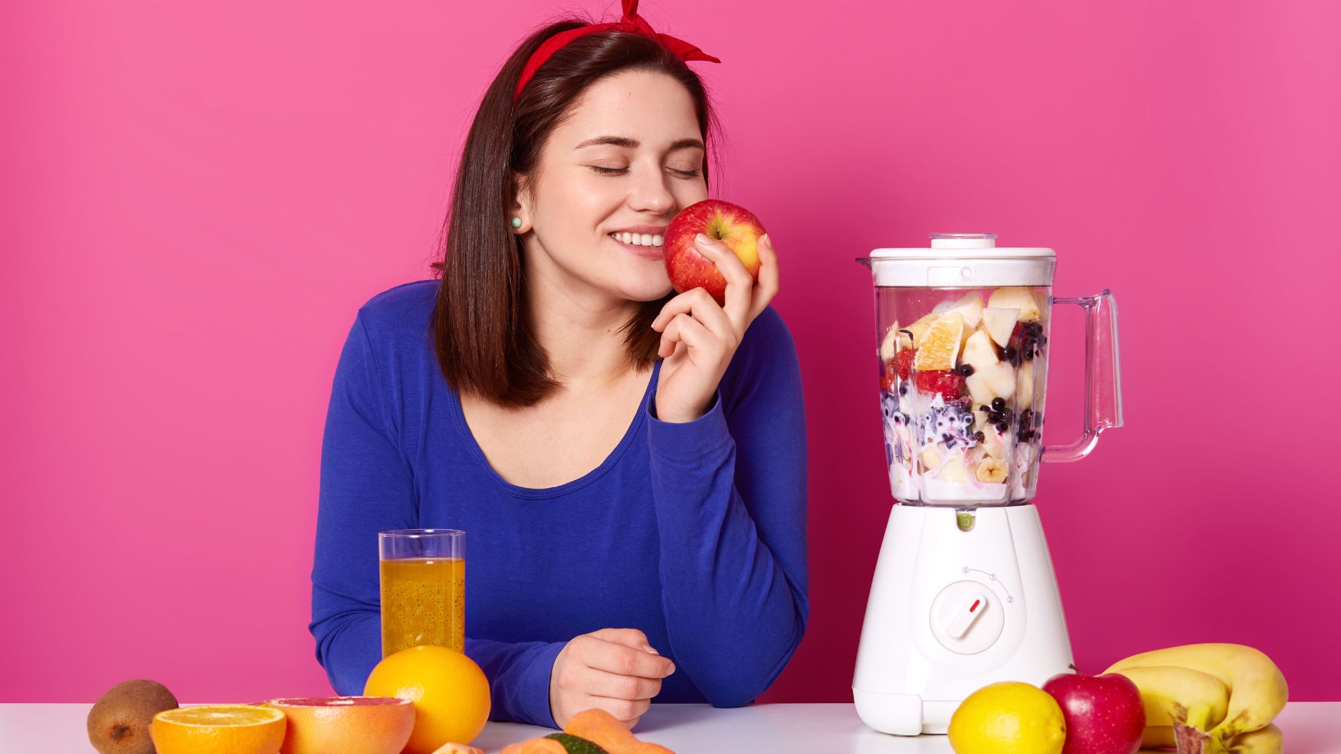 Beautiful Woman Makes a Smoothie with Blender in Kitchen. Brunet