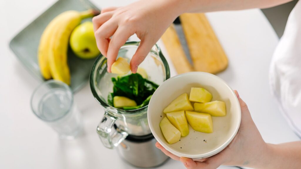 Process of preparing green detox smoothie with blender. Vegan drinks. Concept of mindful eating
