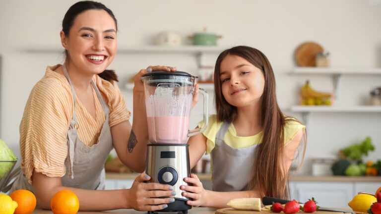 Little Girl and Her Mother Making Smoothie with Blender in Kitchen