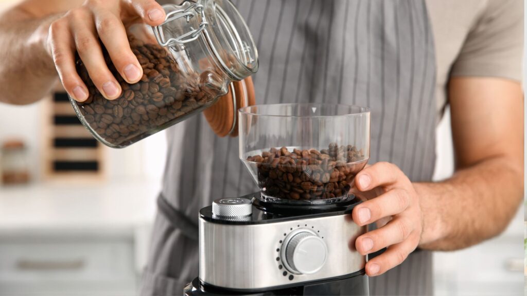 Man Using Electric Coffee Grinder in Kitchen, Closeup