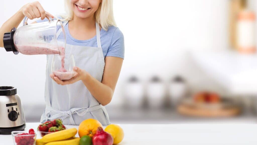 Smiling Woman with Blender and Fruit Milk Shake