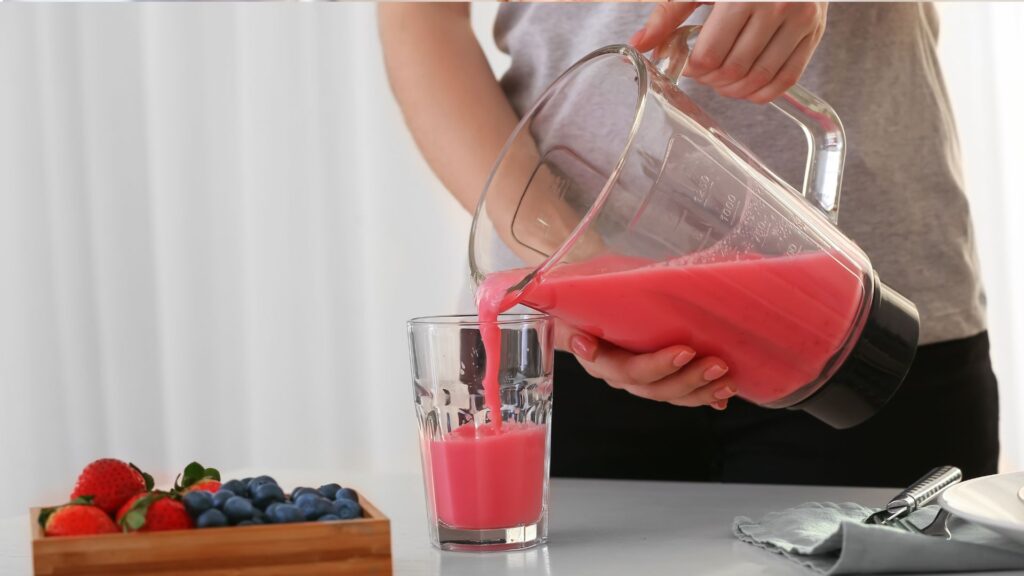 Woman Pouring Healthy Smoothie into Glass in Kitchen
