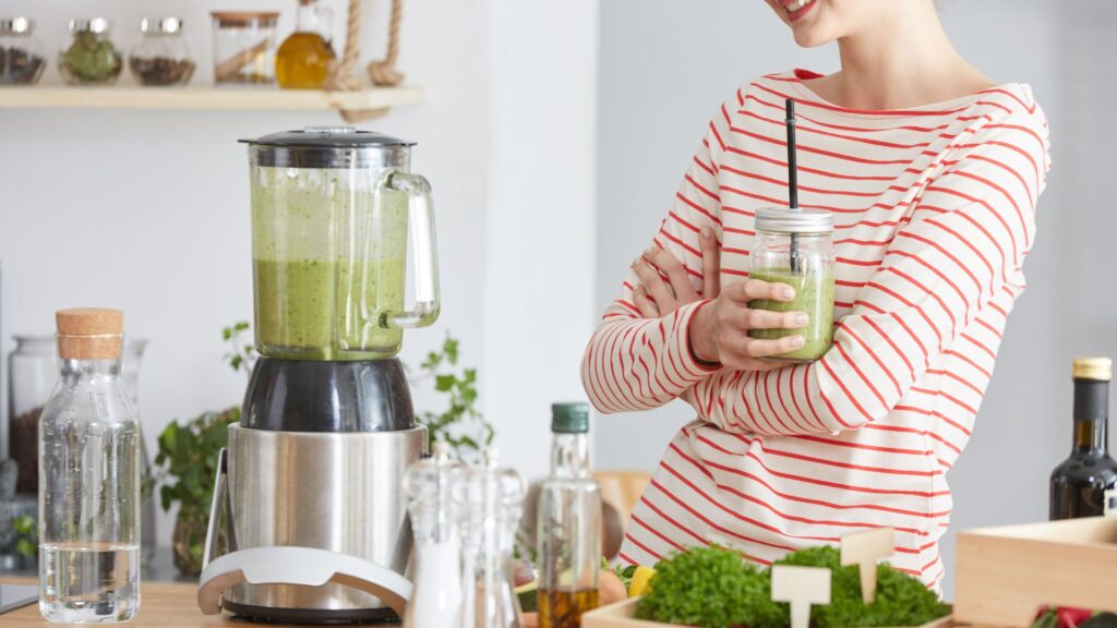 Woman drinking smoothie with blender 