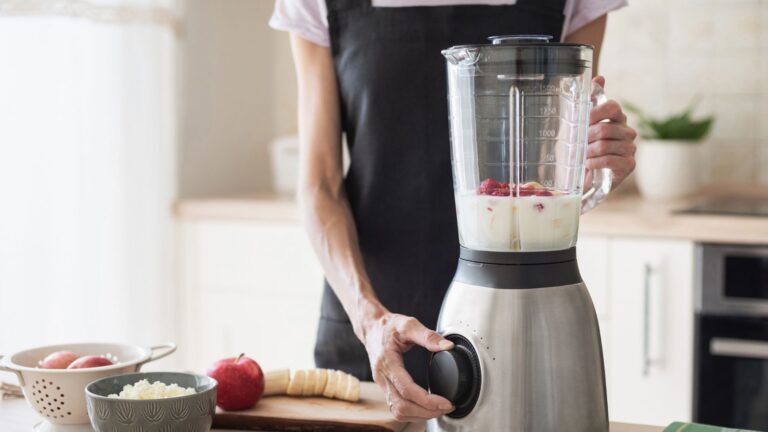 Woman preparing smoothie using blender